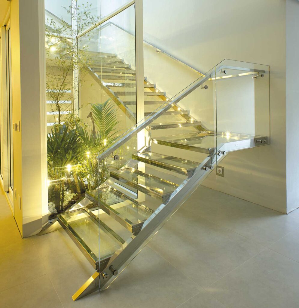 Escada construída em aço inox com guarda-corpo em vidro e corrimão tubular em aço inox.